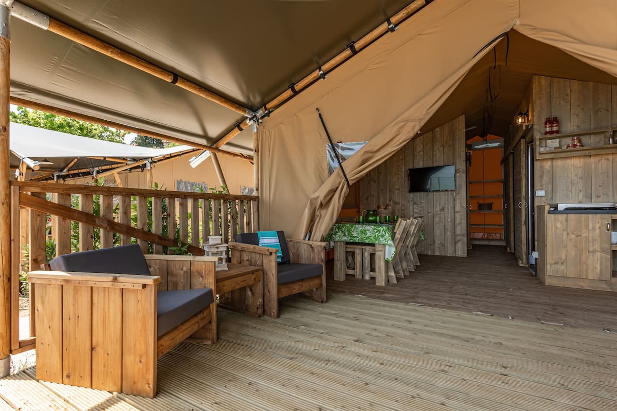 Una terraza de madera con zona de estar cubierta y una mesa.