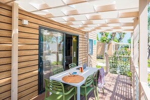Une terrasse couverte avec une table et des chaises, un ordinateur portable et un set de table en fibres tressées.
