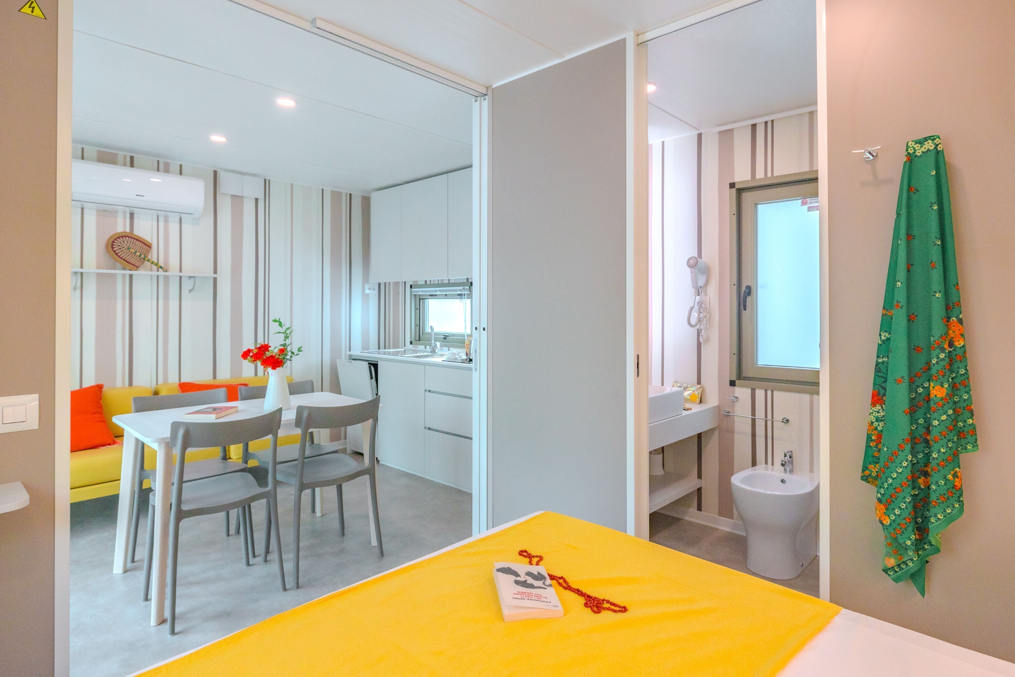A hotel room with a bed, a dining area, a kitchenette, and a bathroom.