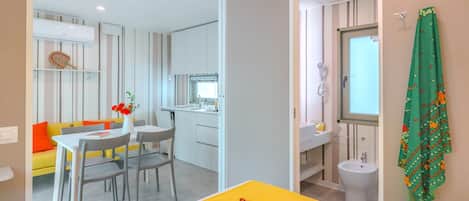A hotel room with a bed, a dining area, a kitchenette, and a bathroom.