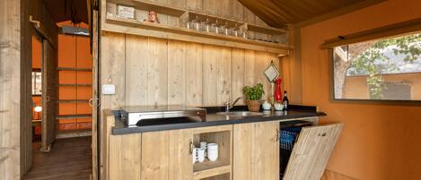 A wooden kitchen with a black countertop, a sink, and a window.