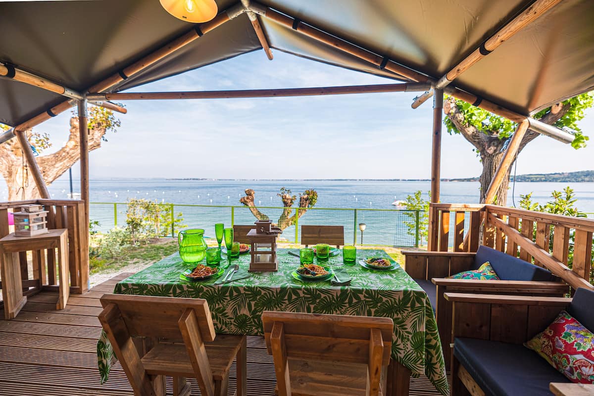Un área de comedor al aire libre con una mesa preparada para dos, con vista a un cuerpo de agua.