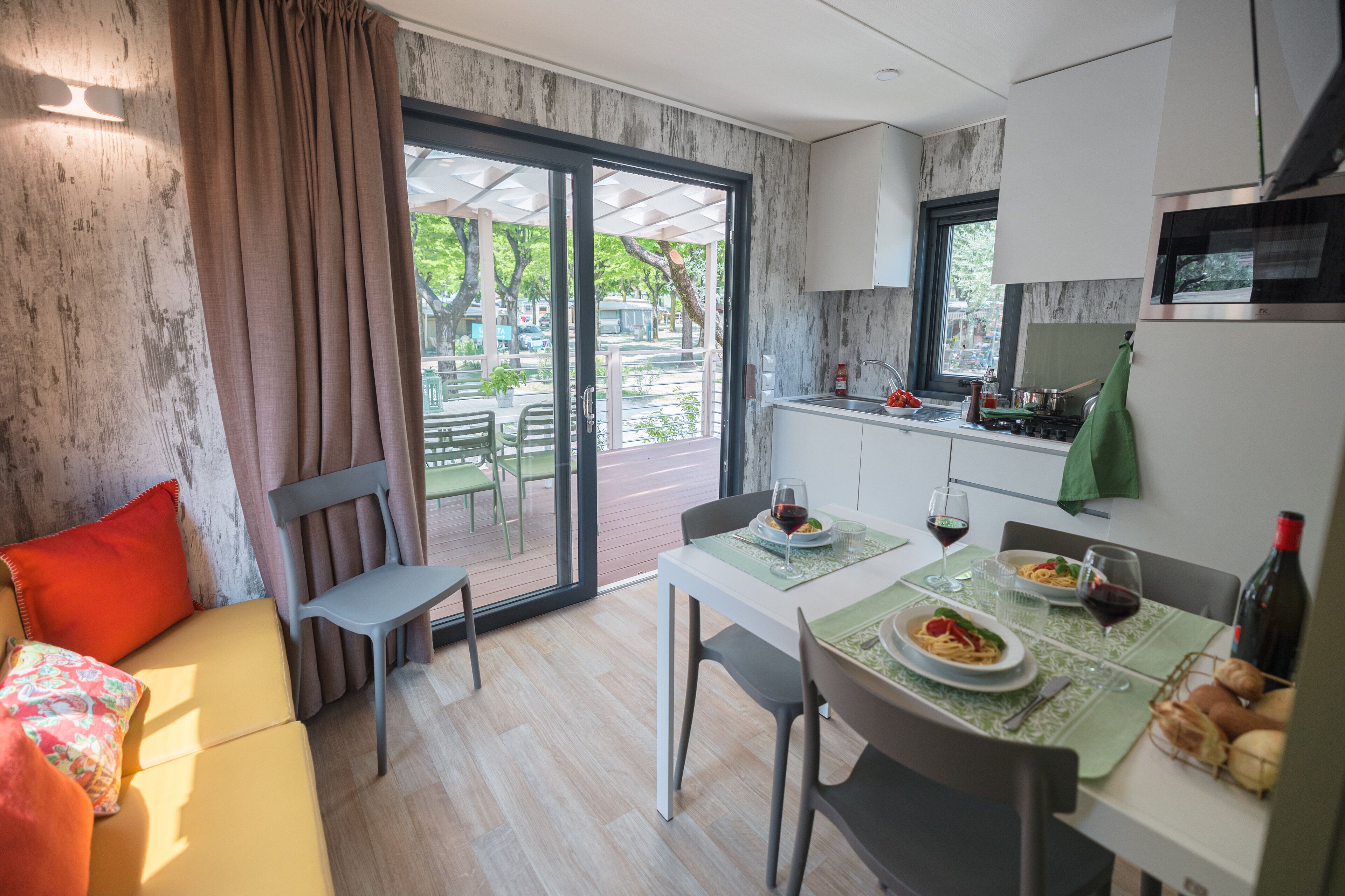 A modern kitchen with a dining area, featuring a table set for two with wine glasses and plates of food.