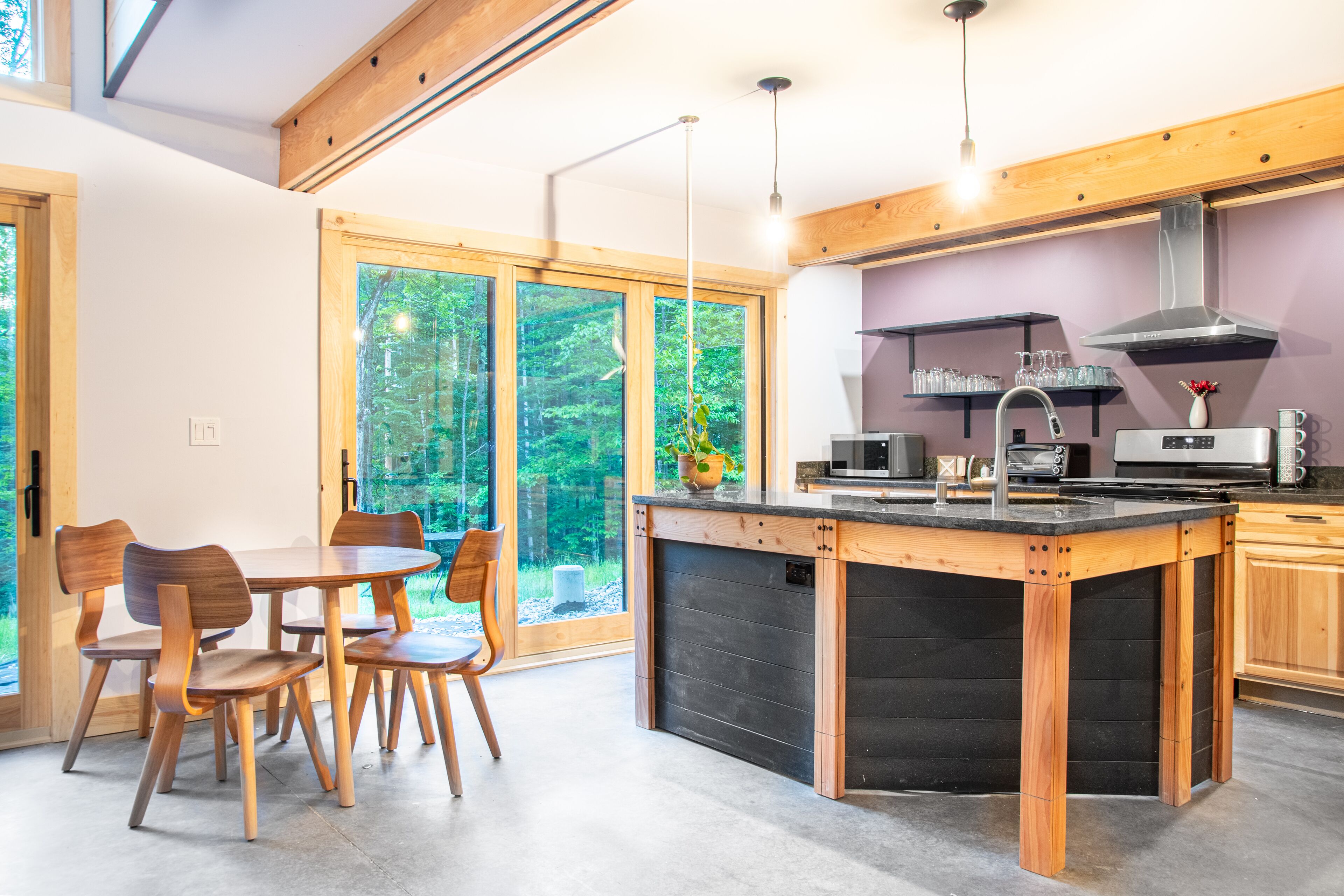 Een moderne keuken met houten kastjes, een centraal eiland en grote ramen met uitzicht op de omgeving.