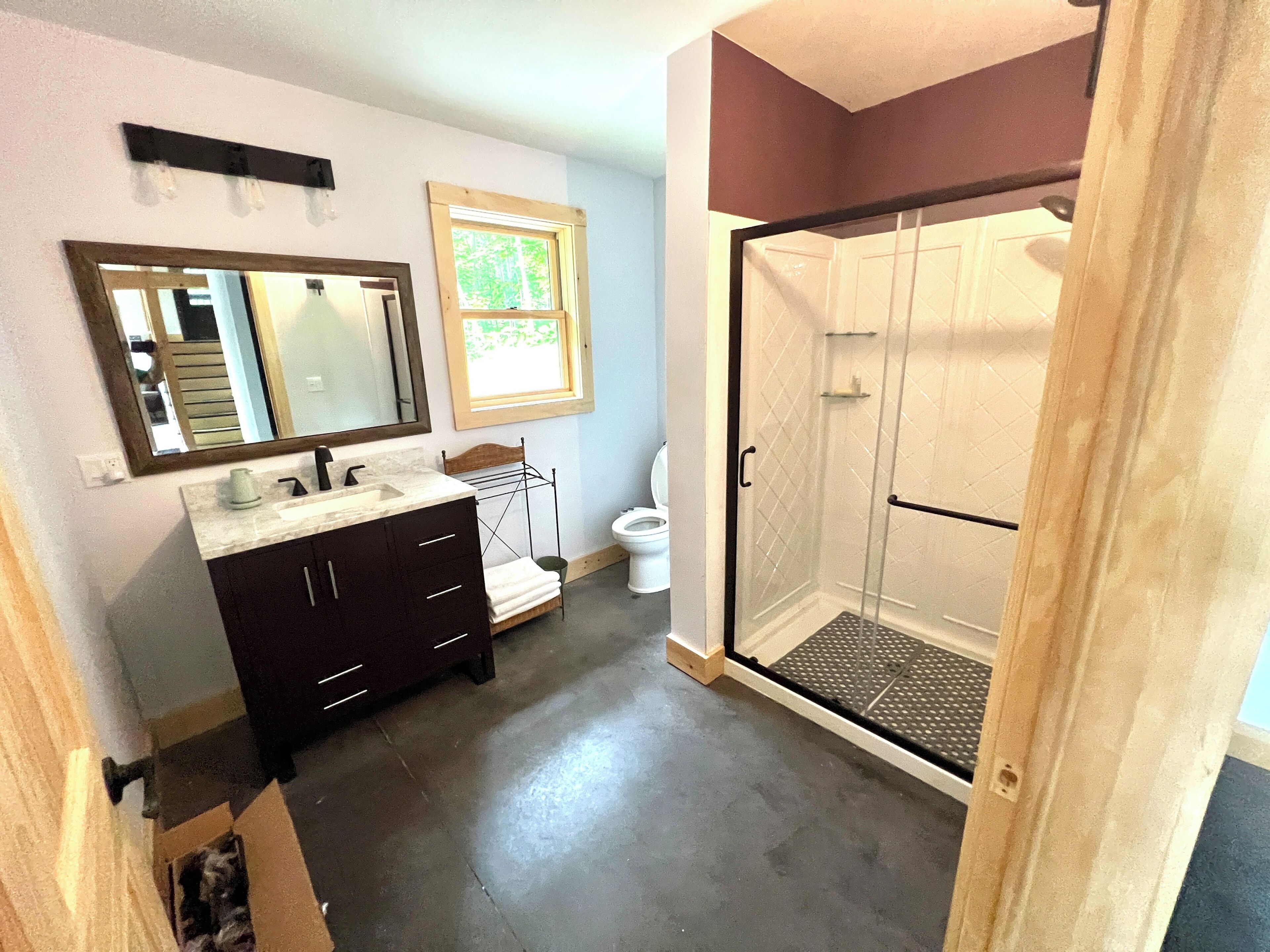 A bathroom with a vanity, mirror, and shower.