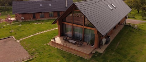 A modern house with a sloped roof, large windows, and a patio area with outdoor furniture.