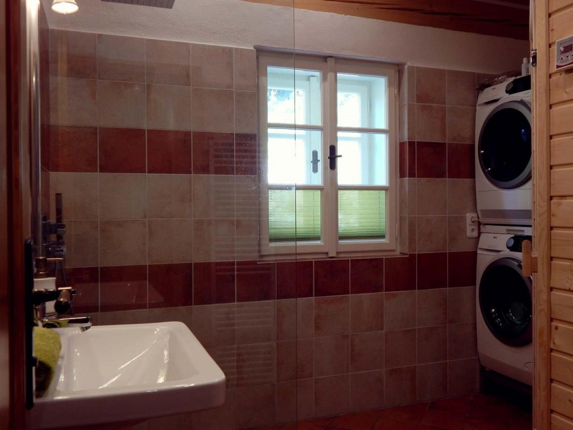 Een badkamer met een wastafel, een raam en een wasmachine.