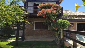 A two-story house with a stone facade, a balcony, and a small garden area. - House 6 bedrooms (4 suites) in Geribá with swimming pool (Cem Bracas Armação dos Búzios)