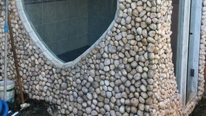 A bathroom with a heart-shaped window and a stone wall. - House 6 bedrooms (4 suites) in Geribá with swimming pool (Cem Bracas Armação dos Búzios)