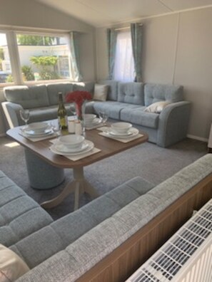 Relax in the spacious living room with a sofa, bench, and dining table, perfect for social gatherings.