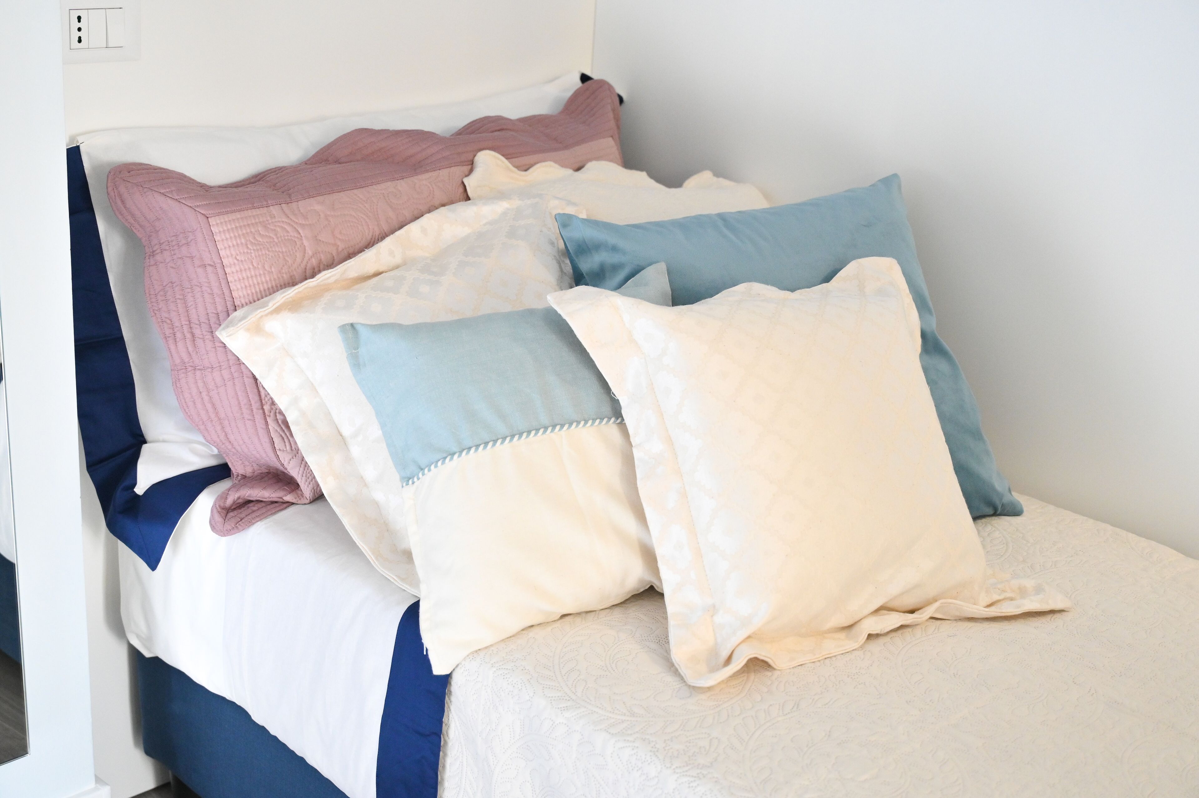 Een bed met meerdere kussens in verschillende kleuren en patronen.