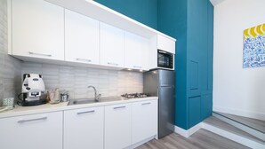 A modern kitchen with white cabinets, a stainless steel refrigerator, and a microwave. - Cozy, new apartment in the historic center and 5 minutes from the beach (Forio)