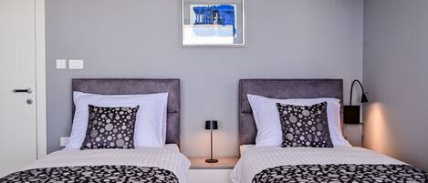 Habitación doble con dos camas, cada una con cubrecama de lunares, una obra de arte enmarcada sobre las camas y una mesita de noche con lámpara entre ellas.