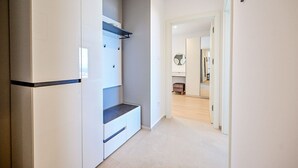 En smal hall med en inbyggd bänk, en vit garderob och en spegel på väggen.