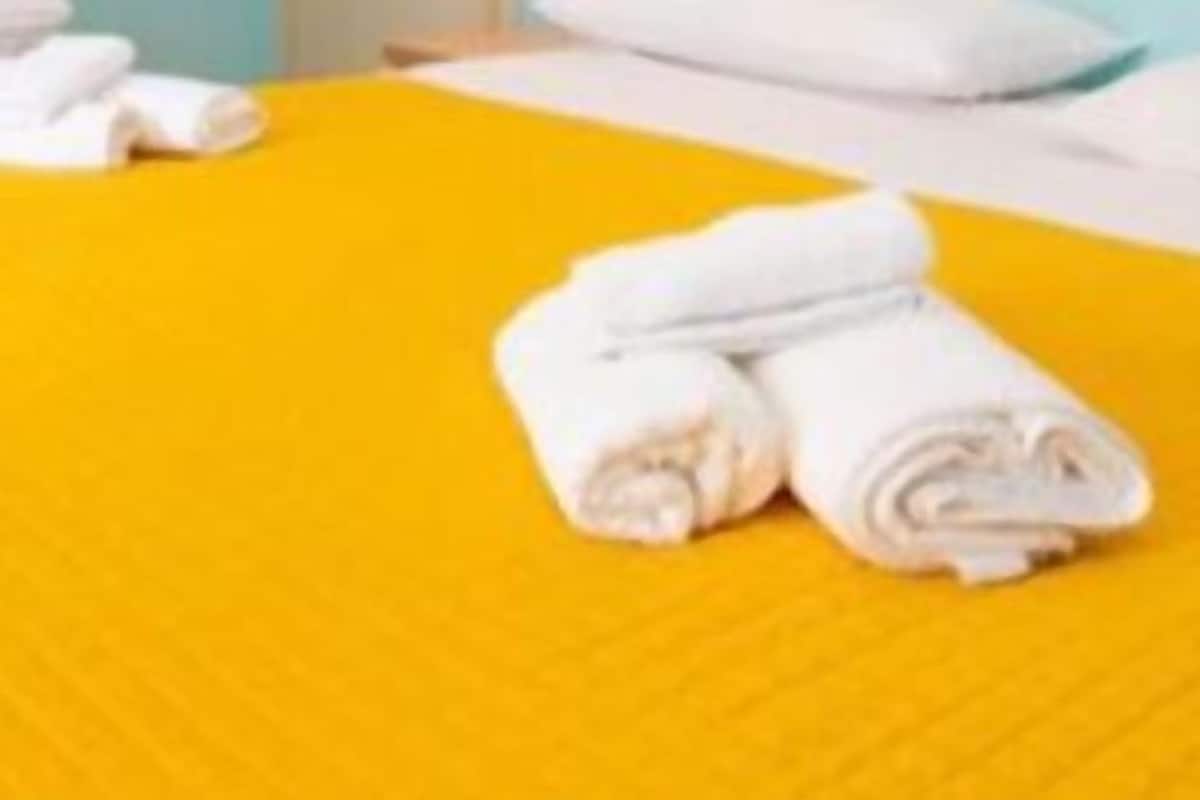 Una habitación de hotel con dos camas, cada una con una colcha amarilla y almohadas blancas.