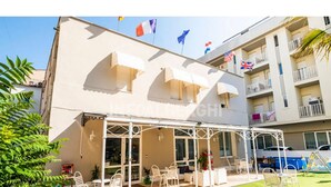 Un hotel con zona de estar al aire libre cubierta, varios balcones y banderas.