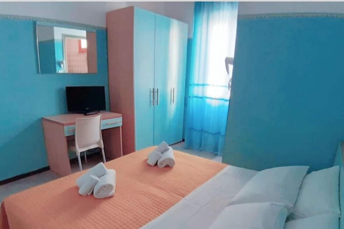 Una habitación de hotel con cama, escritorio, silla y televisión.
