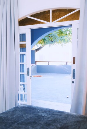 An open doorway leading to a covered outdoor area with a view of a tree and a railing. - Sea Wolf Hostel - Lagoa da Conceição (Florianópolis)