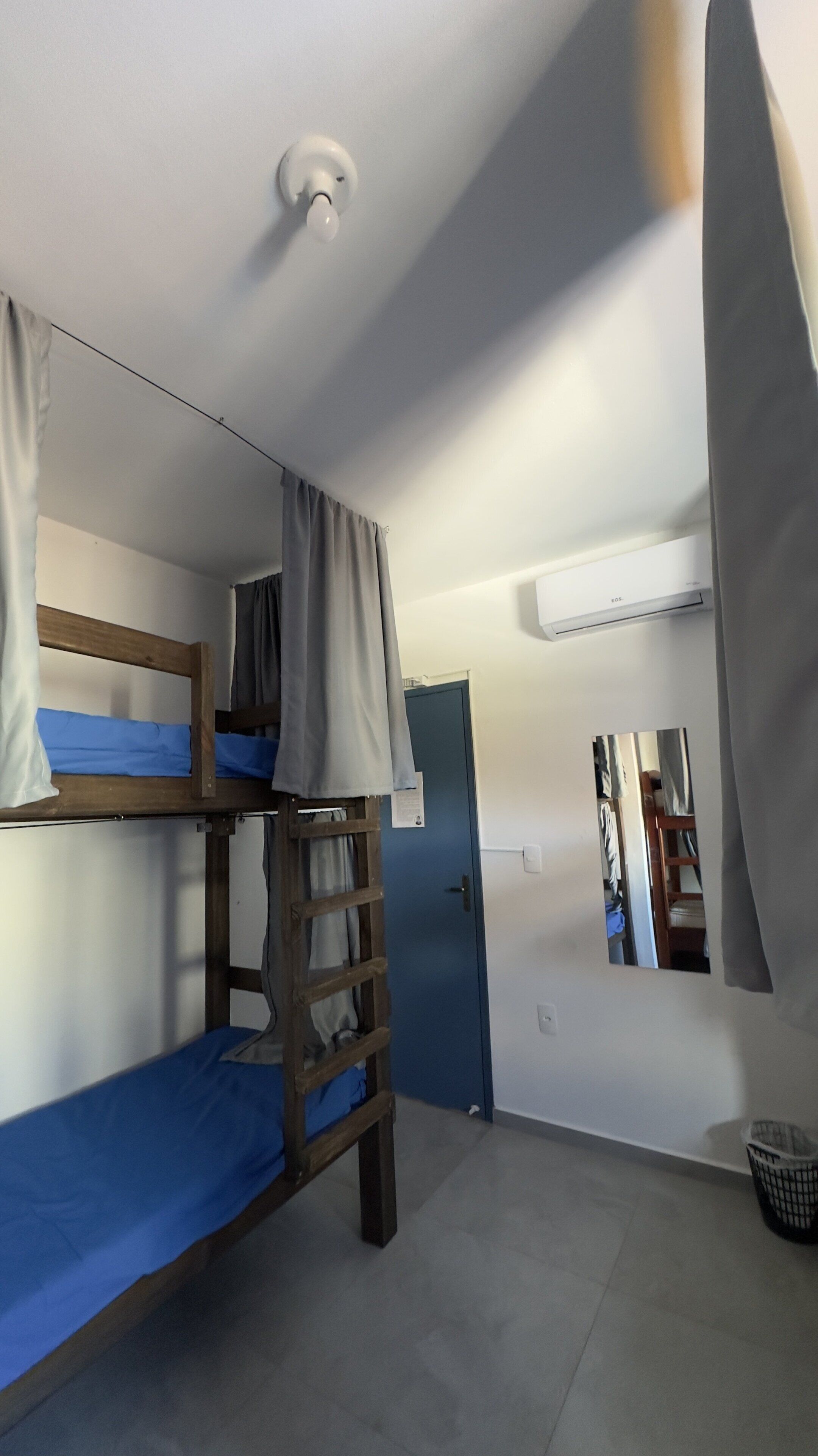 A bunk bed room with a ladder, a door, and a mirror on the wall.