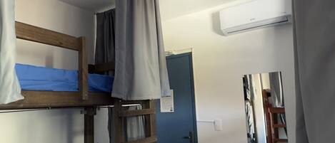 A bunk bed room with a ladder, a door, and a mirror on the wall.