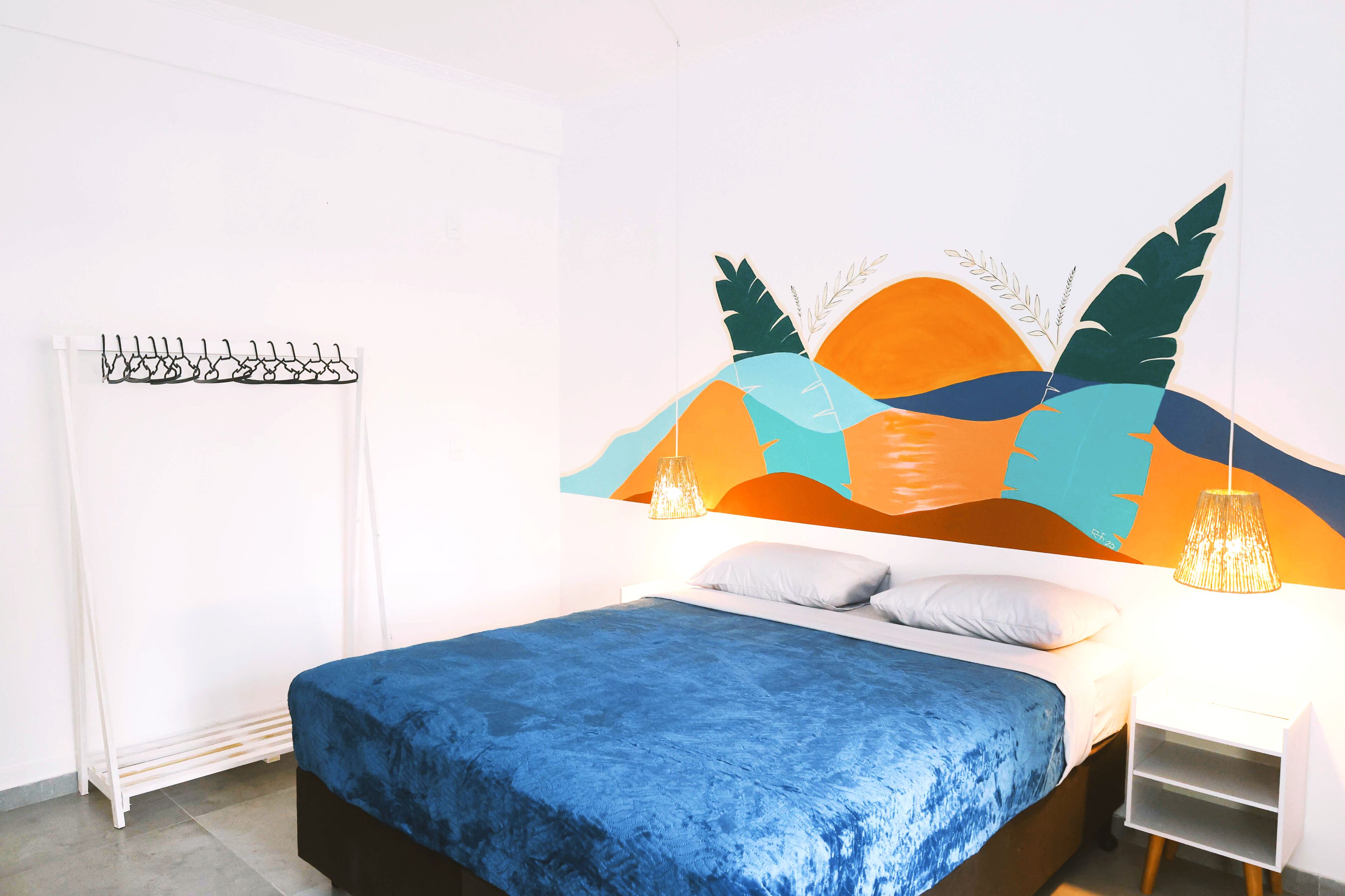 A bedroom with a bed, a white radiator, a wall-mounted light fixture, and a shelf.