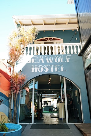 The exterior of the Seawolf Hostel with a clear entrance, a balcony, and a sign above the door. - Sea Wolf Hostel - Lagoa da Conceição (Florianópolis)