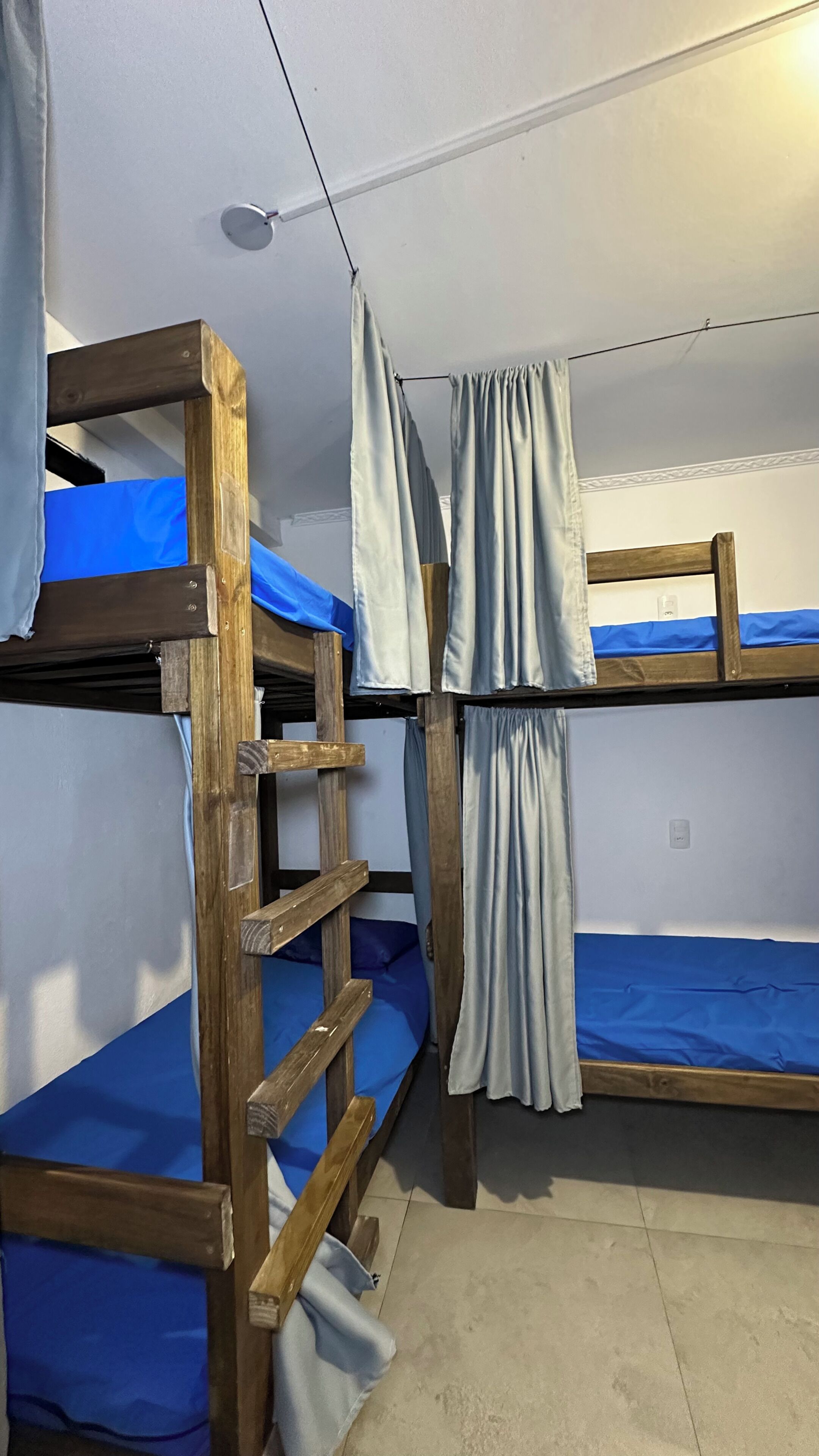 Habitación con literas de madera, ropa de cama azul y cortinas.