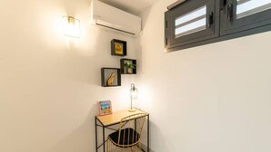 Una habitación pequeña y bien iluminada con un escritorio, una silla y cuadros en la pared.