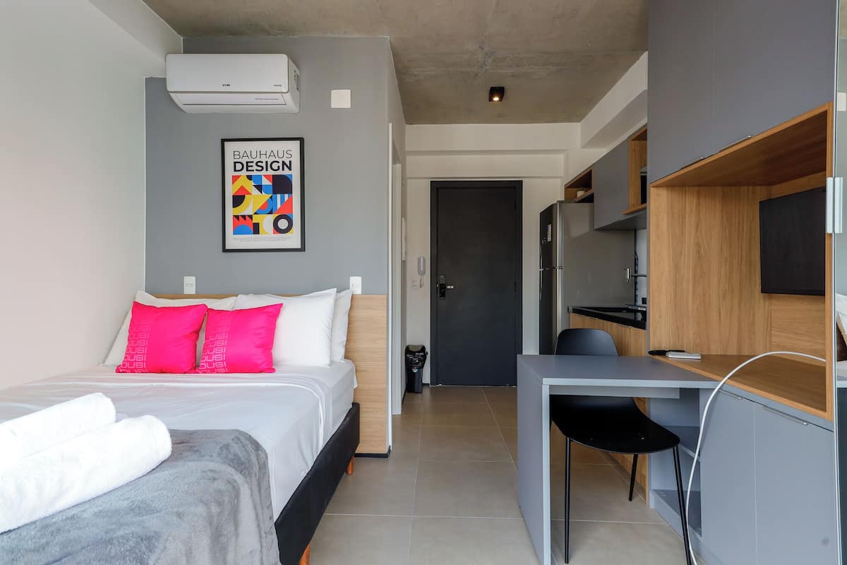Une chambre d’hôtel moderne équipée d’un lit, d’un bureau et d’une kitchenette.