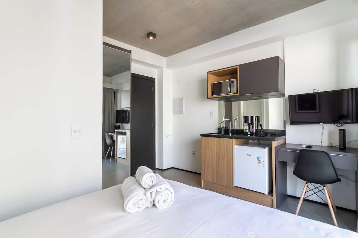 Une chambre d’hôtel moderne équipée d’un lit, d’un bureau, d’une kitchenette et d’une télévision.