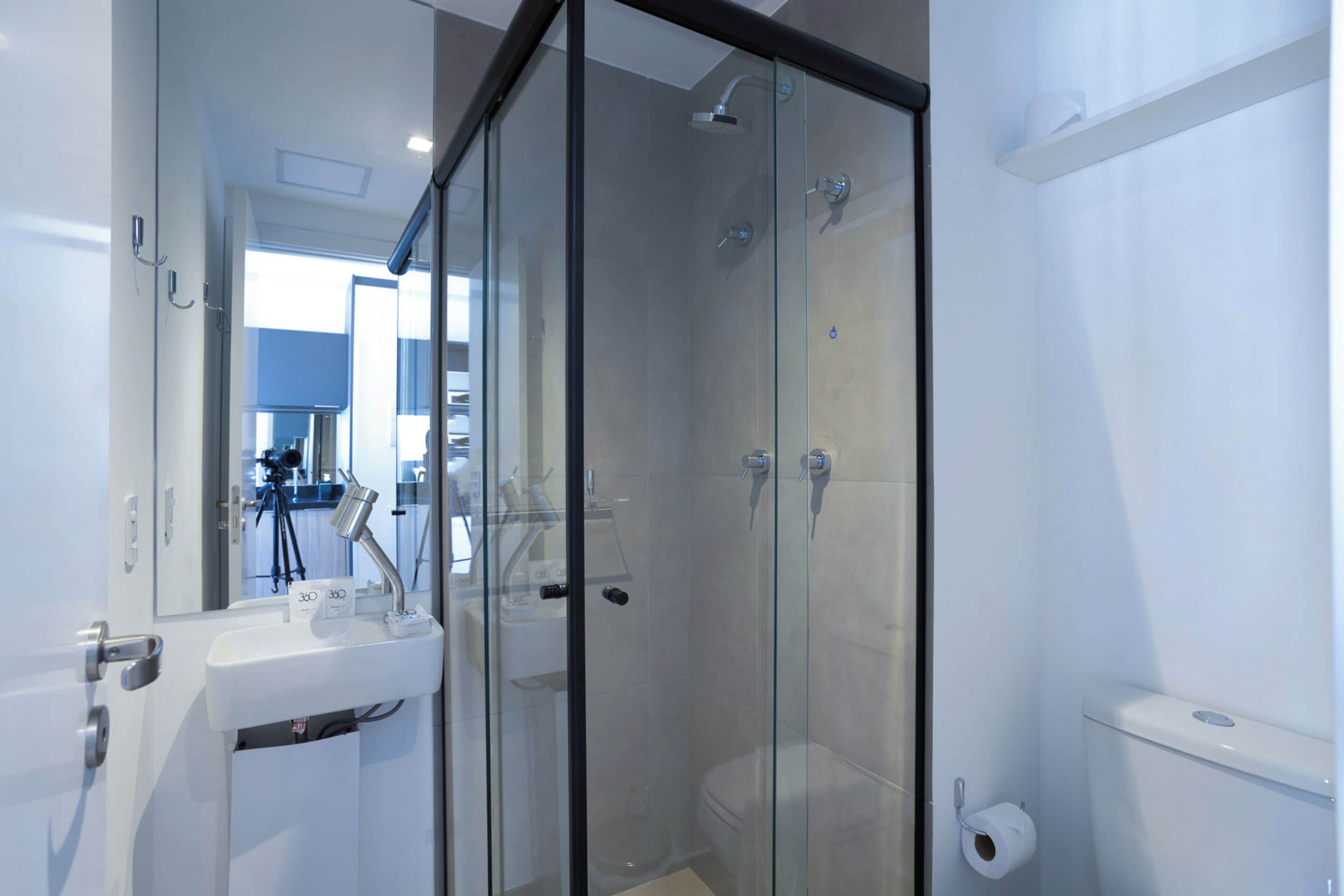 Un baño moderno con ducha de vidrio, un lavabo blanco y un inodoro.