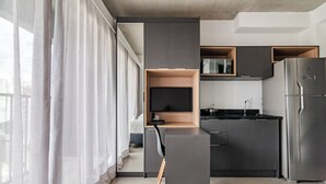Una cocina moderna con armarios oscuros, microondas integrado y refrigerador de acero inoxidable.
