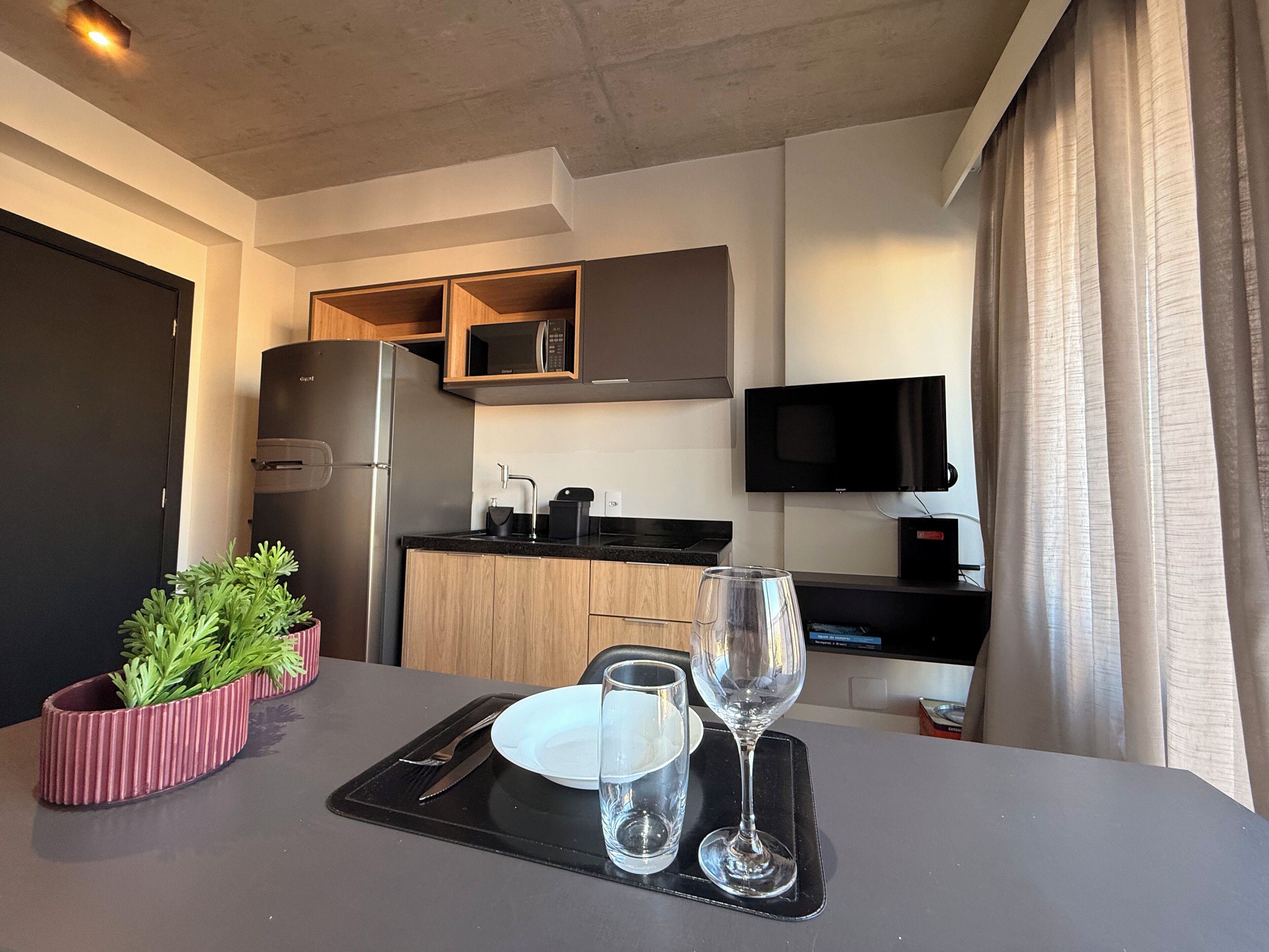 Una cocina compacta equipada con refrigerador, microondas y una pequeña zona de encimera.