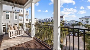 A wooden deck with a swing chair and a view of neighboring houses.