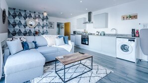 A modern apartment with a living room, kitchen, and laundry area.