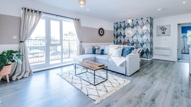 A modern living room with a sofa, coffee table, and a geometric-patterned wall.