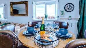 Un coin repas avec une table dressée pour deux personnes, une bouteille de champagne et un panier de croissants.