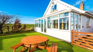 Une maison avec une grande fenêtre en verre, une clôture en bois et une pelouse verdoyante.
