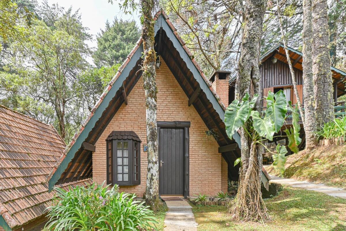 A traditional wooden house with a steeply pitched roof, a brick chimney, and a small window with shutters.