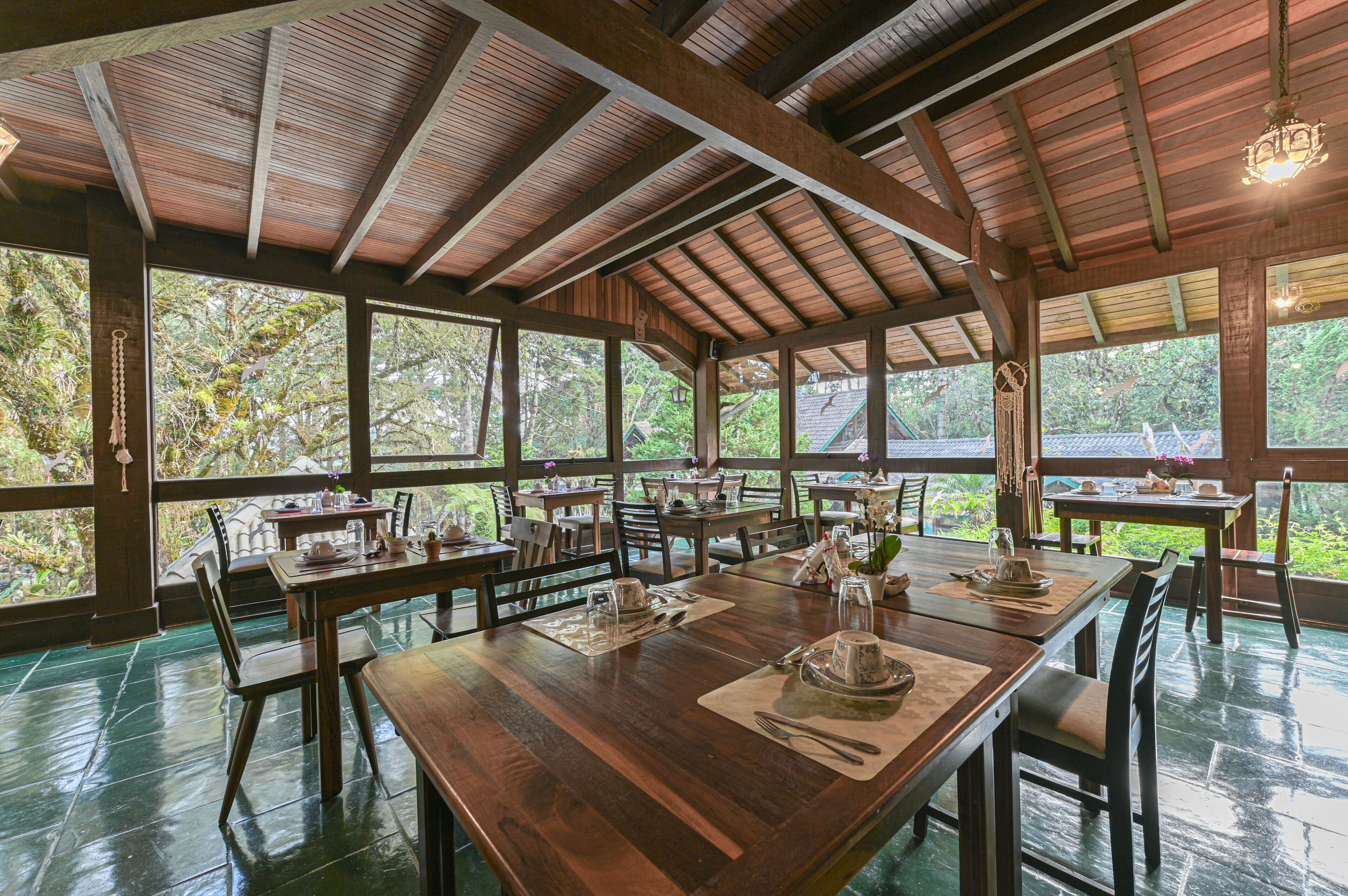 A spacious dining area with wooden tables and chairs, large windows, and a high ceiling.