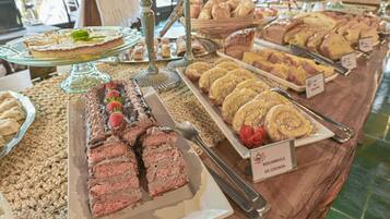 En buffé med olika desserter, inklusive en chokladtårta, en tårta med jordgubbar och en skylt som visar att det finns en sorts bakverk som kallas ”Rocambole de Cocada”.