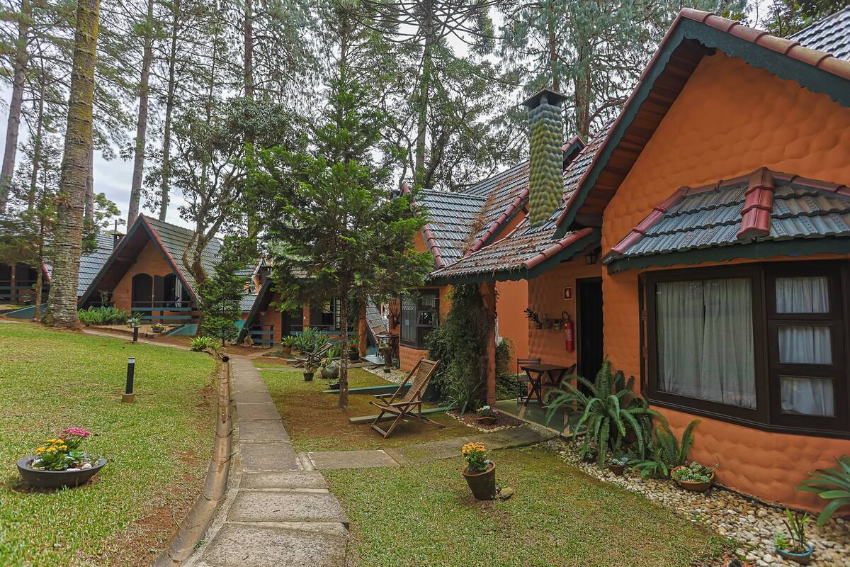 A bungalow-style building with a tiled roof, surrounded by a well-maintained garden with potted plants and a pathway leading to the entrance.