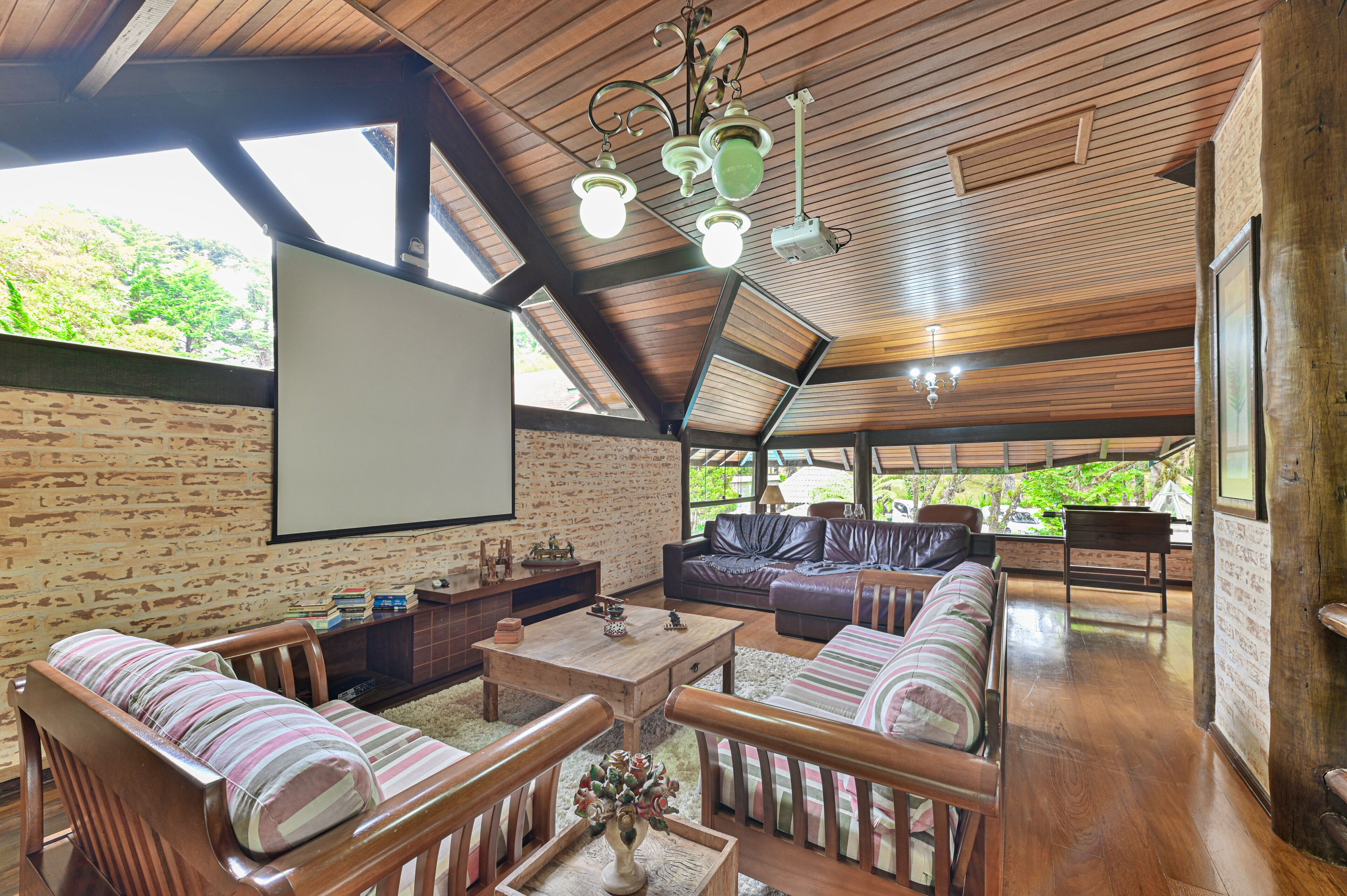 Un vaste espace de vie doté d’un plafond en bois, d’une cheminée, de canapés en cuir et d’un grand écran pour regarder des films ou la télévision.