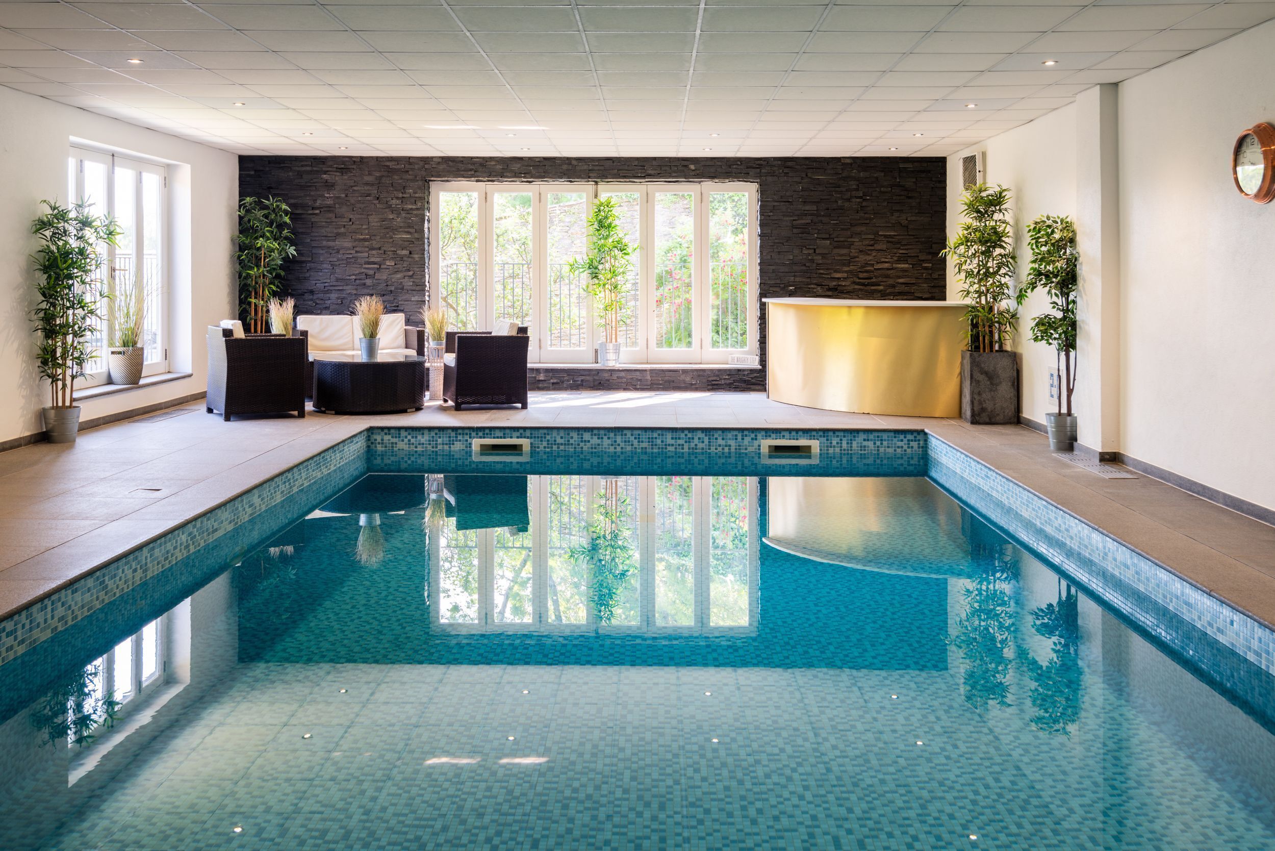 En swimmingpool med flisekant, en reception og plantekasser.