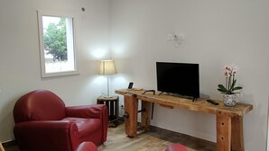 Ett vardagsrum med ett skrivbord i trä, en tv, en lampa och två röda soffor.