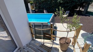 En uteplats med pool, ett trädäck och krukväxter.