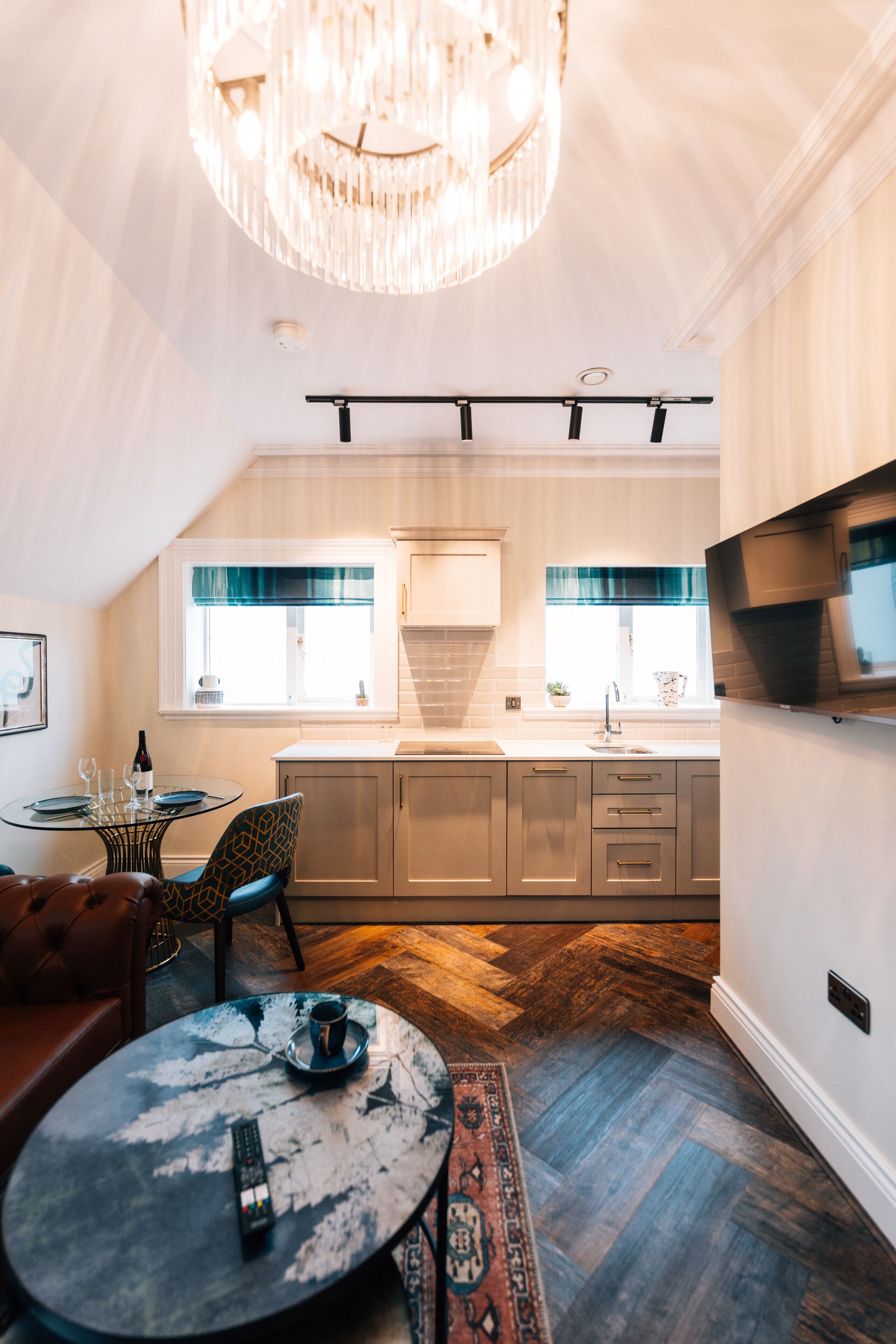 Una cocina moderna con una isla central, un comedor con una mesa redonda y una araña.