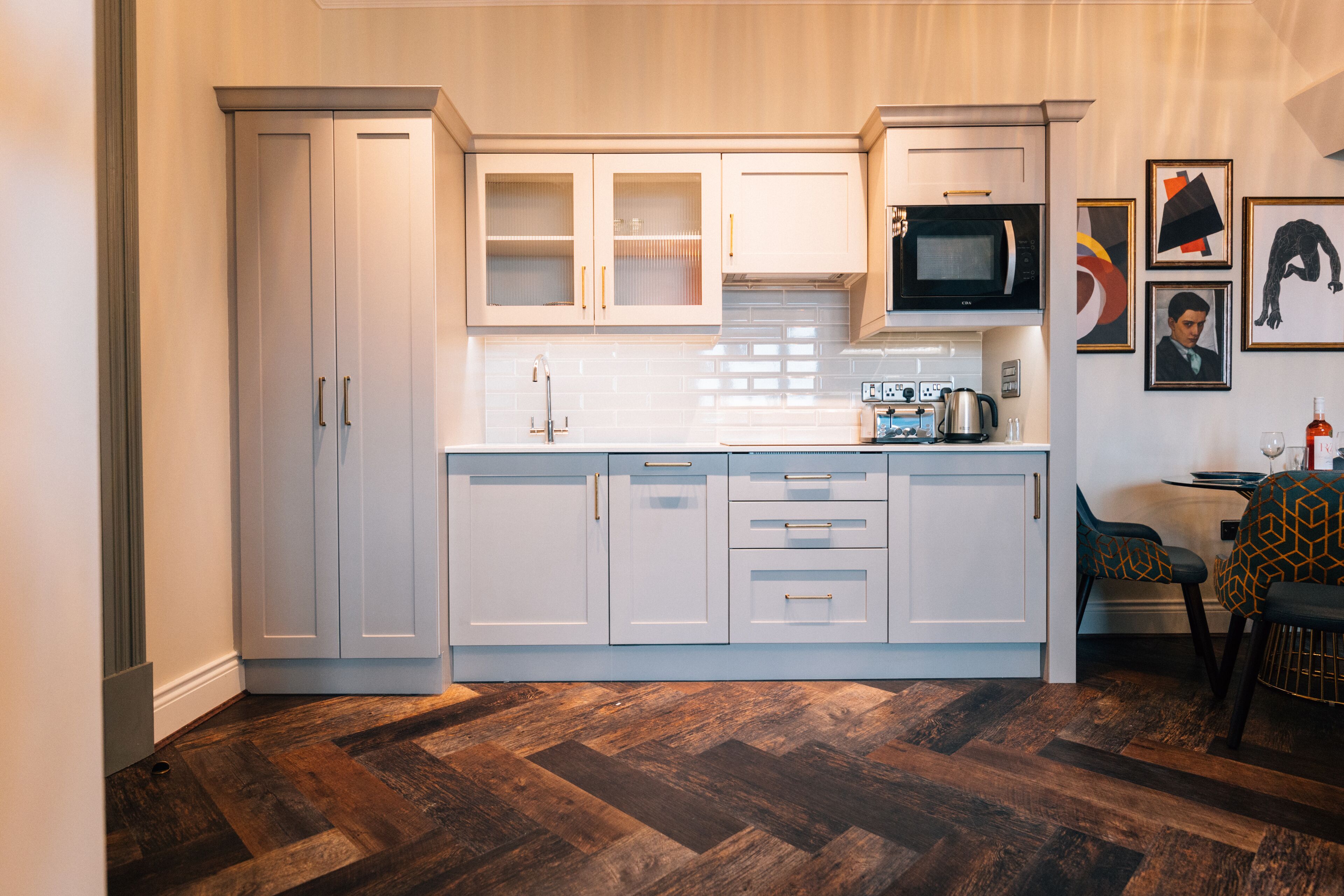 A modern kitchen with white cabinetry, a microwave, and a dining area with patterned chairs.