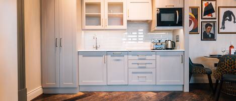 A modern kitchen with white cabinetry, a microwave, and a dining area with patterned chairs.