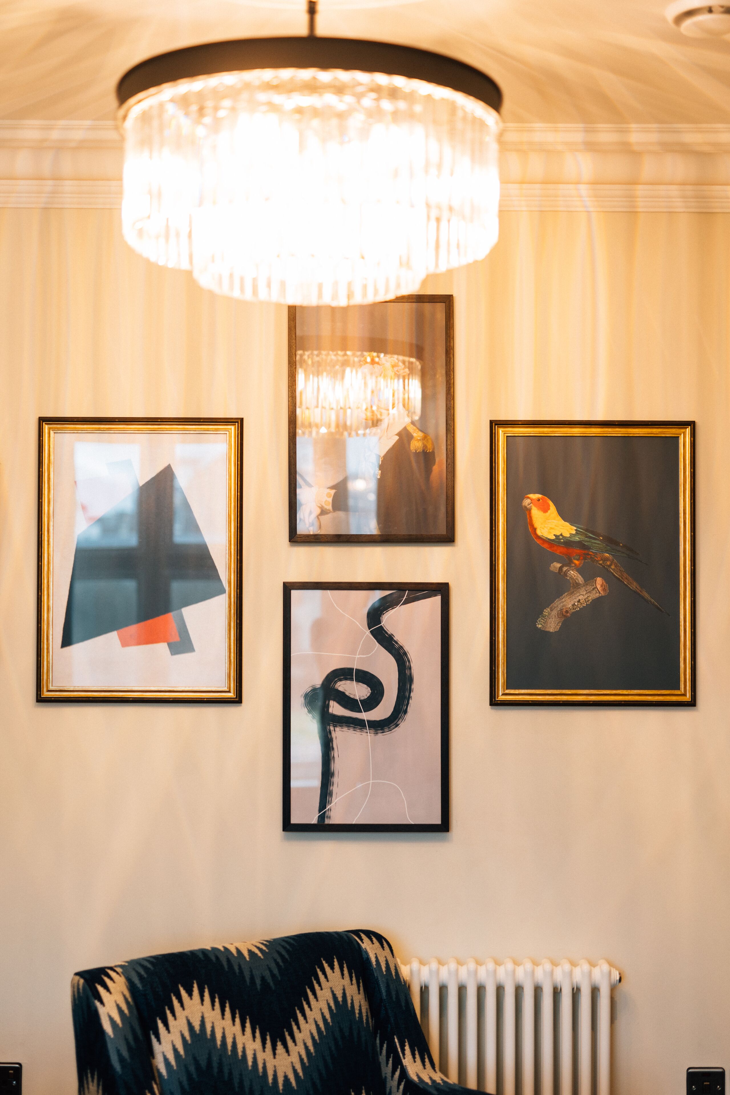 A room with a chandelier, framed artwork, and a patterned sofa.